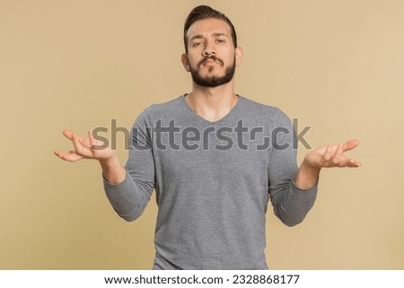 No idea, I dont know answer. Puzzled clueless uncertain lebanese handsome man raising hands in helpless gesture, embarrassed confused by difficult question. Confused one guy on beige studio background