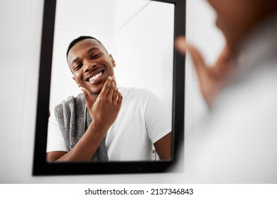 No irritation, no redness. Cropped shot of a young man touching his face while looking into the bathroom mirror. - Powered by Shutterstock