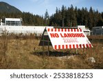 No landing zone sign in front of building and nature background. Large two sided outdoor sign with red letters. Keep area free of aircraft landing. Selective focus.