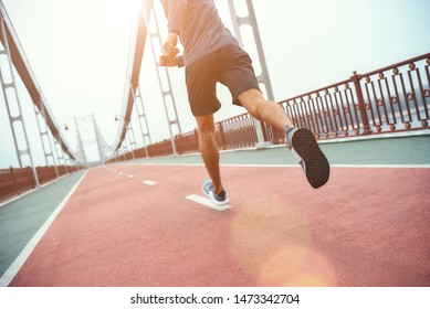 No limits Back view of young handsome man in sports clothing jogging on the bridge in the morning
