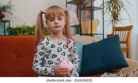 No Money. Frustrated poor little toddler kid girl hold almost empty piggybank with only one dollar cash. Children at home alone. No savings, wrong budget planning, low interest on deposit, bankruptcy