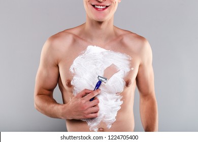 No More Chest Hair! Part Of Handsome Shirtless Young Man Shaving His Chest With Smile While Standing Against Grey Background
