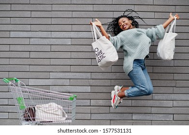 No More Plastic. African Woman With Shopping Cart Trolley And Eco Bags Jump Outdoor Market.