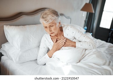 No One Is Immune. Shot Of A Senior Woman Experiencing Chest Pain In Bed In A Nursing Home.