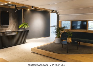 No one is present in this modern office lounge with plants and sofa. Warm lighting complements wooden accents and cozy atmosphere, unaltered - Powered by Shutterstock