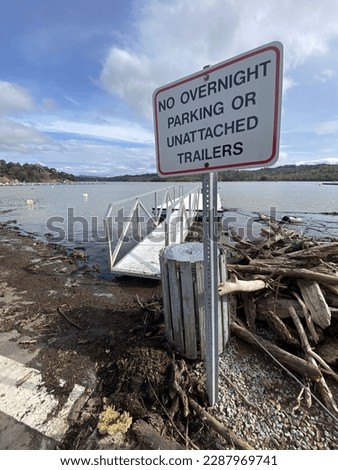 No overnight parking or unattached trailers sign, wood debris, trash can, lake, pier, blue sky, water Stockfoto © 