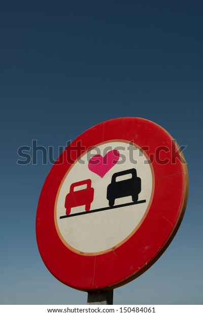 A no overtaking\
road sign with a love heart