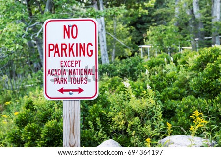 A no parking sign except for tour buses is on the side of the road in Acadia National Park Maine because thousand of tourists flock to the park in the summer.