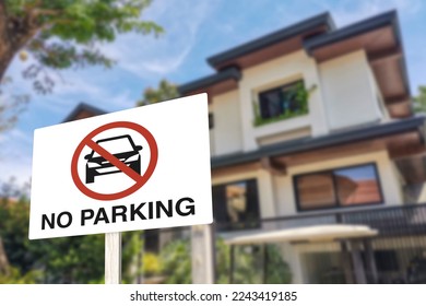A no parking sign in front of a gated house. A warning prohibiting vehicles blocking the gate or the side of the road.