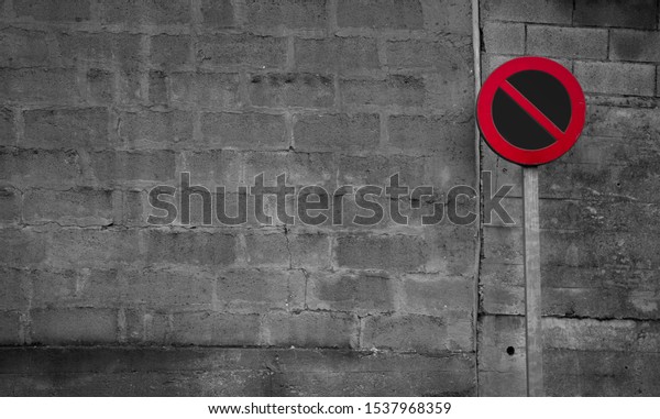 No\
parking sign. Regulatory sign. Circle red and black no parking sign\
on post. Traffic sign on gray and white brick wall background. Road\
signs for prohibit car parking. Restrictive signs.\

