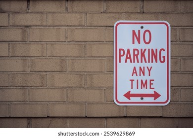 No Parking Sign white with red letters on a brown brick wall with copy space. - Powered by Shutterstock