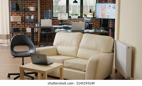 No People In Empty Workplace With Couch And Computers, Interior Decor With Technology Used To Plan Business Charts And Graphs. Nobody In Creative Startup Office With Financial Statistics.