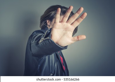 No pictures, please. Celebrity is hiding face with a hand from newspaper photographers.