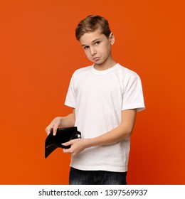 No Pocket Money. Sad Teen Boy Showing Old Empty Wallet, Orange Studio Background