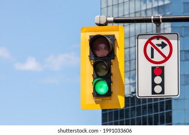 A No Right Turn On Red Pictograph Sign Next To A Traffic Signal Showing A Green Go Light