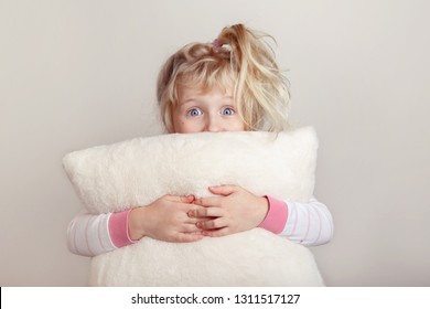 No Sleeping Insomnia Concept. Cute Funny Adorable Excited Surprised Blonde Caucasian Girl Child With Wide Open Eyes Embraces Holding White Soft Fluffy Pillow. Kid Does Not Want To Sleep