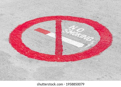 No Smoking Sign With A Crossed Out Cigarette In A Red Circle Painted On A White Wall