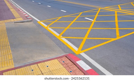 No stopping yellow crisscross zone traffic sign on asphalt road surface at the entrance or exit way of hospital with yellow tactile paving line for the blind and visually impaired on sidewalk - Powered by Shutterstock