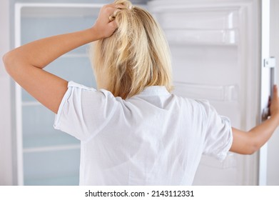 No Temptations During Her Diet. Rearview Of A Young Woman Looking In Her Empty Fridge.