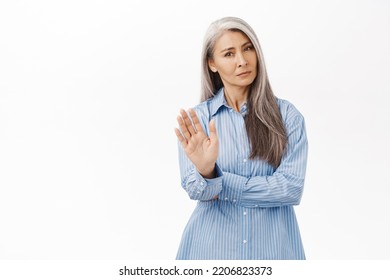 No Thank You. Asian Senior Woman With Grey Hair, Showing Stop, Rejectiong Gesture, Wave Hand To Refuse Smth, Standing Over White Background.