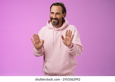 No Thanks Pass. Charming Polite Manly Adult Bearded Man Grey Hair In Pink Hoodie Apologizing Refusal Raise Palms Rejection Gesture Declining Offer Smiling Say Sorry Not Interested, Purple Background