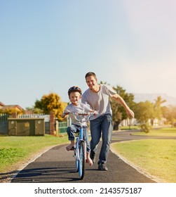 No Training Wheels Needed. Shot Of A Father Teaching His Little Son How To Ride A Bicycle In The Park.