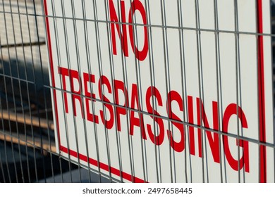 no trespassing sign tied to a mesh wire fence at a construction site