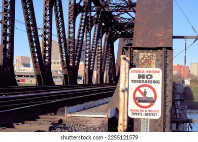 A No Trespassing warning sign posted at the entrance of an aging railroad bridge.