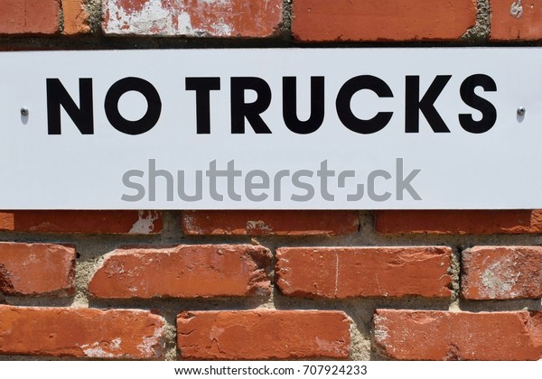 No trucks, white sign on the brick wall, forbidden\
parking for trucks