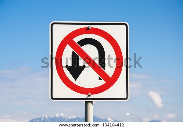No U Turn road sign\
against the blue sky