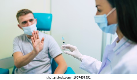 No Vaccination. Scared Man Gesturing Stop To Hand Offering Syringe With Vaccine Refusing To Be Vaccinated. Needle Phobia, Fear Of Covid-19 Vaccines