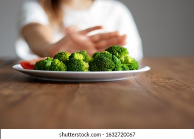 No Vegan Diet Concept. Teen Girl Pushing Away Plate With Broccoli And Other Vegetables Refusing To Eat. Food Waste. Copy Space. Selective Focus On Food. 