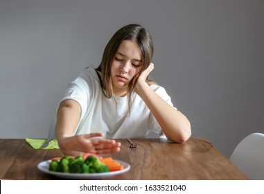 No Vegan Diet Concept. Teen Girl Pushing Away Plate With Broccoli And Other Vegetables Refusing To Eat. Food Waste. Selective Focus On Girl. 