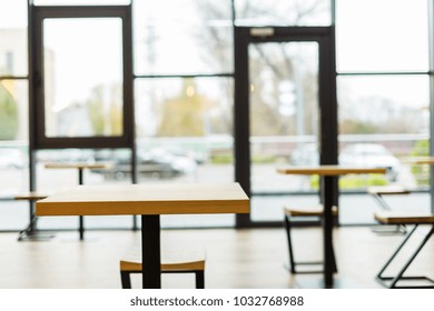 No visitors. Close up of an empty table in the cafeteria with a big glass wall in the background