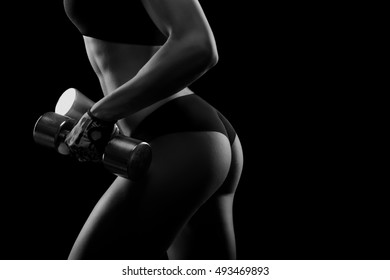 No Way Back. Black And White Closeup Shot Of A Perfectly Shaped Flawless Backside Of A Young Sportswoman With Dumbbells In Her Hands