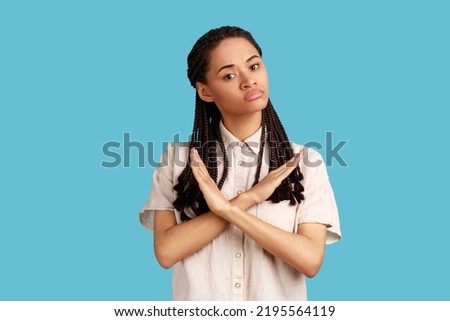 No way, never again. Portrait of determined serious woman with black dreadlocks crossing hands on chest, gesturing x sign, stop this is finish. Indoor studio shot isolated on blue background.