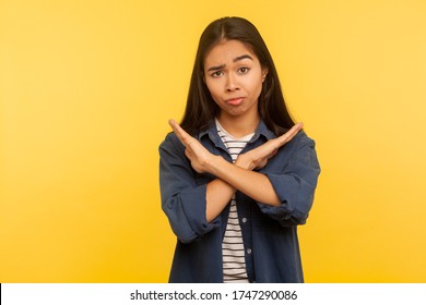 No way, this is finish! Portrait of dissatisfied girl in denim shirt gesturing stop, x sign with crossed hands, way prohibited, warning of troubles. indoor studio shot isolated on yellow background