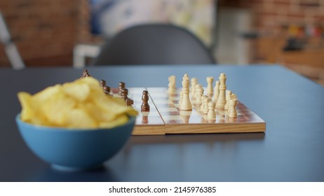 Nobody In Apartment With Snacks And Wooden Board Games For Friends To Meet And Play Chess Game For Leisure Activity. No People At Empty Table With Tactics Play And Bowl Of Chips. Close Up.