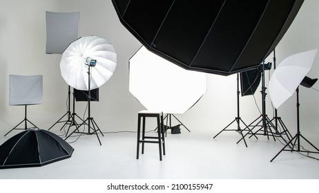 Nobody in empty photographer photography shooting studio workplace set full of equipment flash softbox led halogen lighting reflect umbrella reflection strobe tripod on white backdrop background.