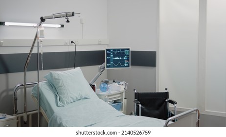 Nobody In Hospital Ward With Bed And Heart Rate Monitor For Reanimation And Healthcare. Empty Emergency Room With Medical Instruments And Equipment For Intensive Care. Space For Recovery