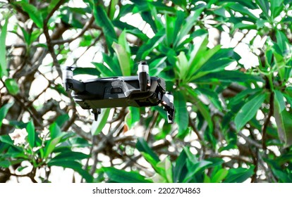 Nobody, Modern Black Drone Flying In Nature With 4 Propellers, 4k Camera Photo, And Video. The Concept For Professionals In The Unmanned Aircraft Technology Industry. Close Up, Crop, Blur Background.