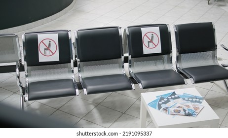 Nobody Sitting On Empty Chairs At Facility Waiting Room Area During Covid 19 Epidemic, Interior Of Medical Space. No People In Hospital Reception And Counter, Coronavirus Pandemic.