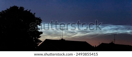 Noctilucent clouds shown above rooftops after dark, bright withe icy clouds at the edge of space in the upper atmosphere, space for text, only seen during summer months when conditions are right