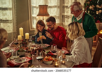 Noel afternoon family gathering. Cheerful grey-haired grandparents, young adult couple and boy at house feast party, sitting  and talking, eating delicious food and enjoying holiday - Powered by Shutterstock