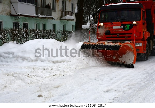 Noginsk,\
Moscow Region, Russia-JANUARY 22, 2022: During a snowfall, a large\
red snowplow with a scraper clears the road from snow. Large\
snowdrifts. Russian winter in the\
province