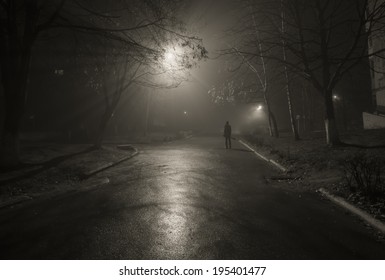 Noir. Silhouette of a passerby on the night street. Black and white