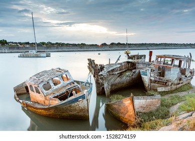 The Noirmoutier boats cemetery early in the morning. A group of wrecks of old wooden fishing boats stranded in the mud is illuminated by the port lights. - Powered by Shutterstock