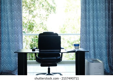 A Noise Effect And Backlight Picture Of Simple Office With Table,laptop, Notebook, Coffee Cup, Chair, Air Purifier And Big Sliding Door Insight. Home Office Concept.