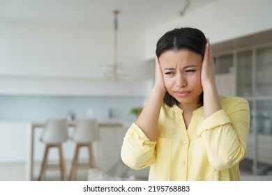 It Is Noisy, Displeased Nervous Girl Closes Ears. Conceptual Portrait Of Young Emotional Woman. Advertising Banner Mockup. Attractive Spanish Girl In Yellow Shirt. Modern Interior Of Apartment.