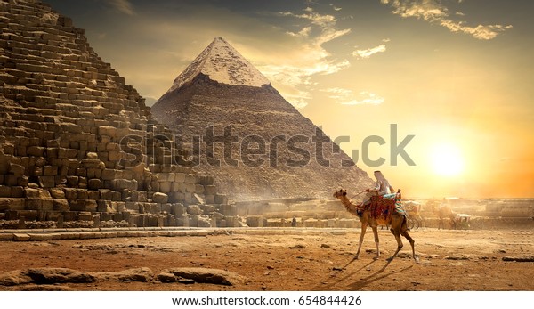Кочевник на верблюде возле пирамид в египетской пустыне